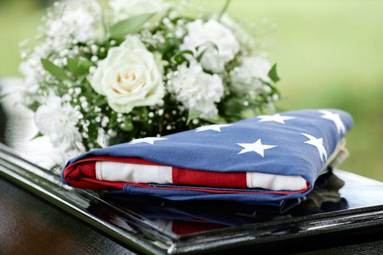 Featured image for VA Burial Benefits, showing a casket with flowers and a flag of the United States on top